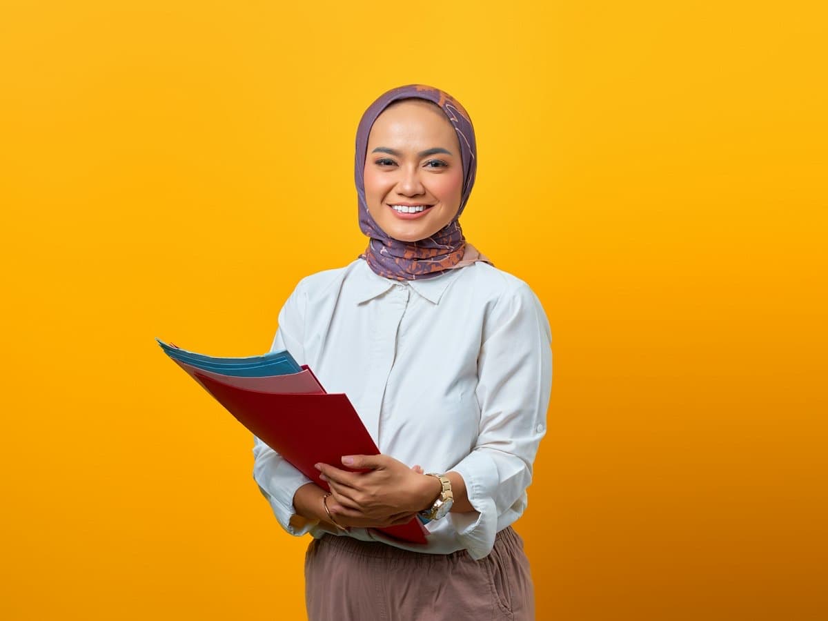 Smiling Malaysian consultant holding training plan folders